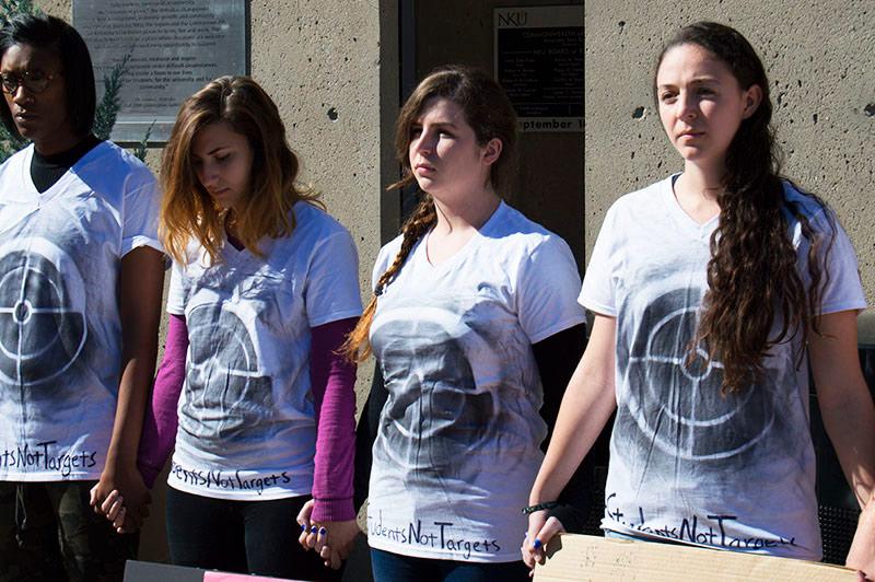 A line of individuals standing in protest against gun violence.