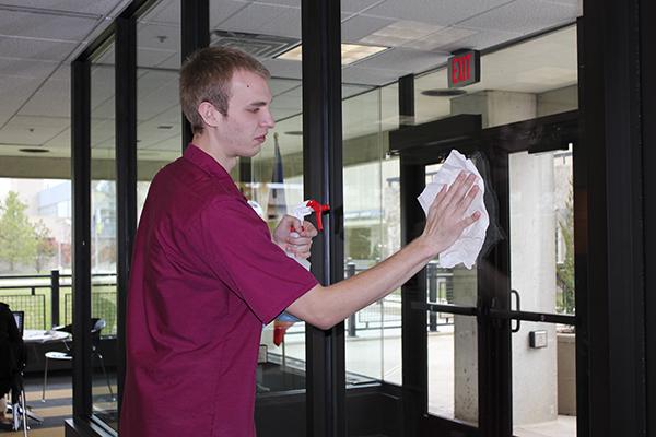 Corbin Ash-Fox cleans a window on campus. Ash-Fox works as a custodian on campus while taking courses as well.
