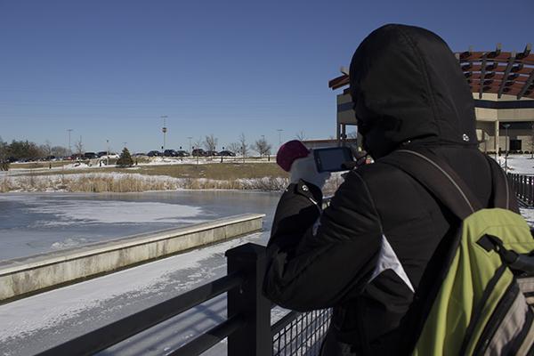 Freshman biology major, Amy Brown, takes a picture to share on her phone of NKU’s frozen campus lake, Loch Norse. 