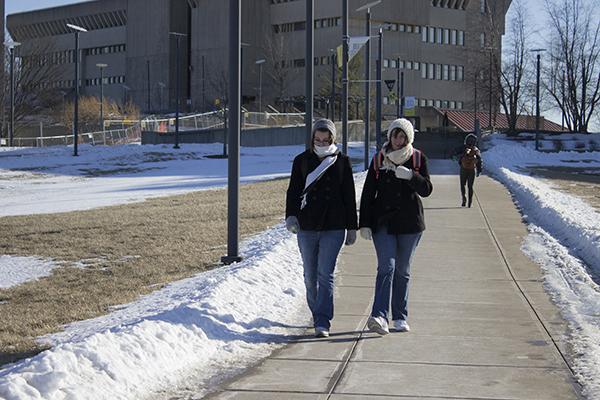  To manage the cold, juniors Kelly Trumbo and Emily Zeisler keep warm by covering up and limiting skin exposure while traveling outside on campus.