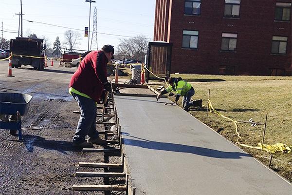 Worker lays down concrete outside of Callahan Hall. 