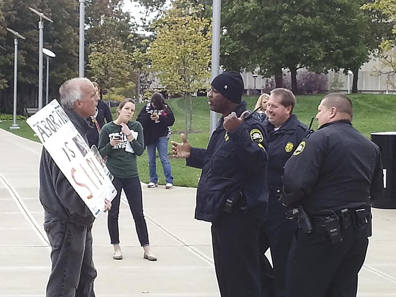 Campus police inform abortion protestor that he needs to relocate to a free speech zone on campus.