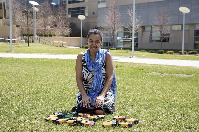 Senior studio arts major Lwam Eyassu with some of the disposable cameras used for her 100 Voices project. 