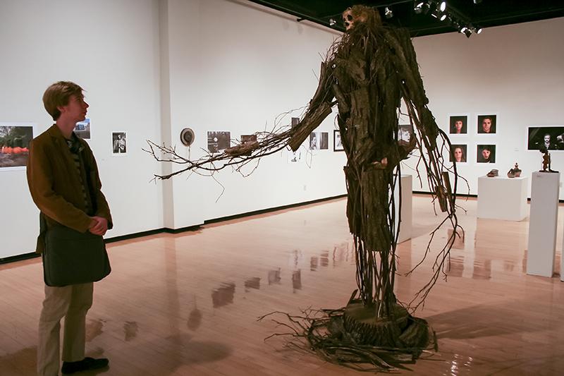 Michael Loftus, freshman, looks at Guardian of the Wood statue in the gallery.