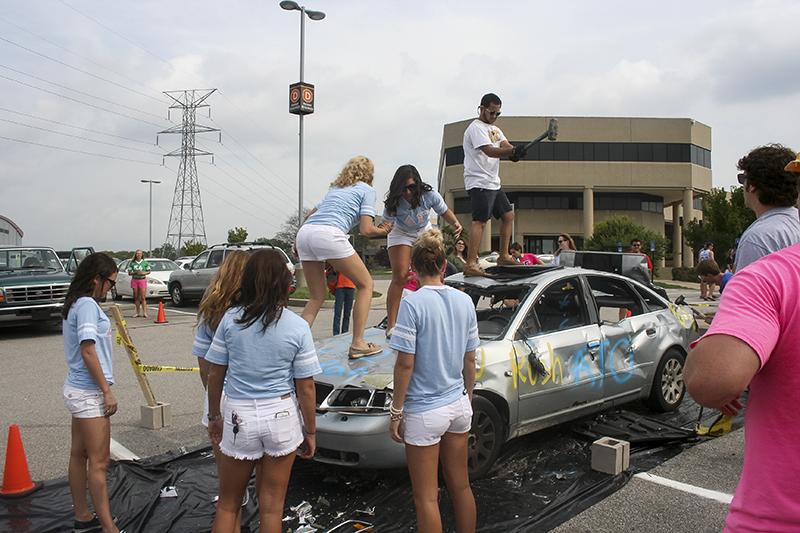 Delta Gamma sorority girls taking a swing at a car.