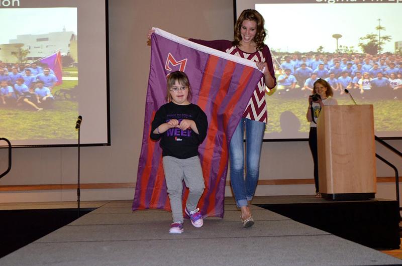 Best Buddies Vice President Summer Buchanan accompanies 4-year-old Ellie Hammond on the runway. 
