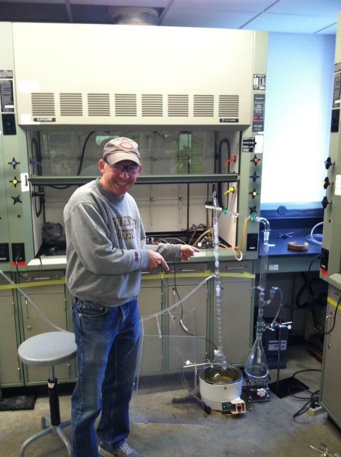 NKU Chemistry professor KC Russell poses with Matthew Miles' machine. Russell has been supporting Miles in the creation of the machine.