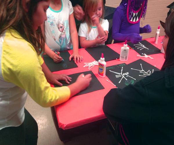 Community children and volunteer NKU makes cotton swab skeletons during Norse-O-Ween event.