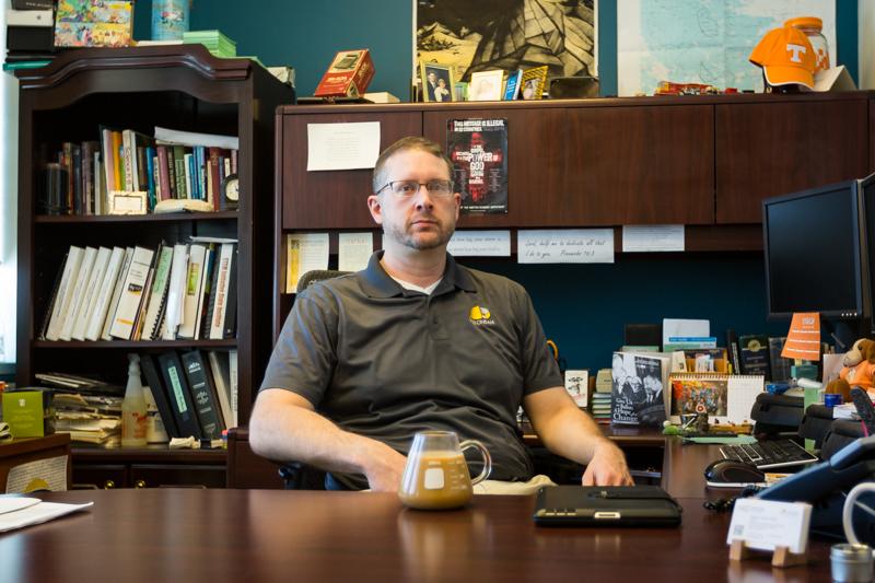 John Farrar sits in his office, which is decorated with collectibles from his travels.