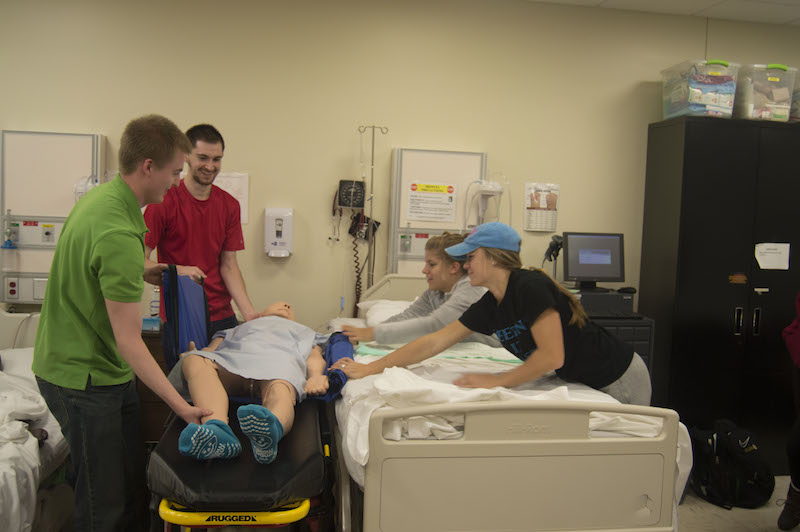 First-year nursing students transfer a mannequin in a skills lab. 