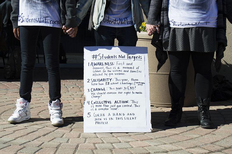 Students stand during the silent protest bringing awareness to school shootings and gun violence. The protest was organized by Students for Social Change.