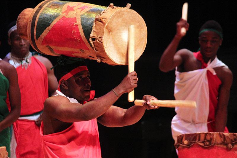 Burundian drummer performs while balancing a drum on his head 
