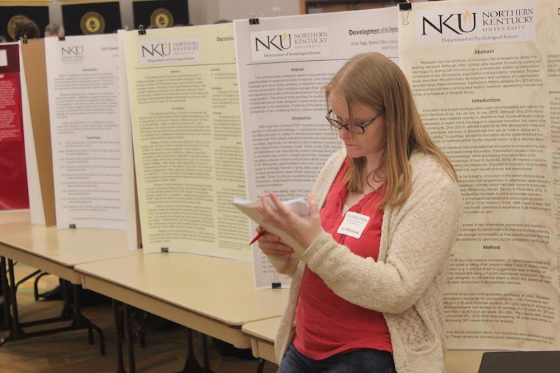 Participants, students and staff walk around to view others research findings and projects.