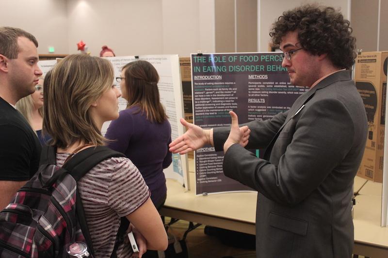 A student discusses their poster and research with others at the Celebration Poster event.