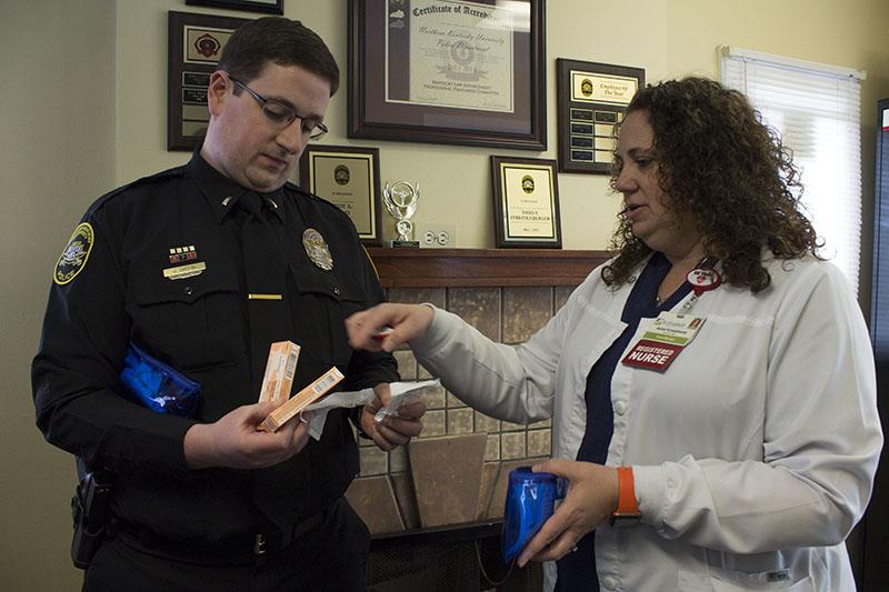 Ashel Kruetzkamp, nurse manager of the emergency department at St. Elizabeth in Edgewood, shows Lt. John Gaffin the contents of a naloxone kit. NKU officers were equipped with naloxone on April 1. 