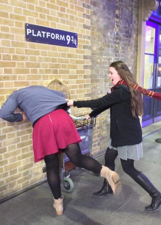 Two students pose at the platform 9 3/4 entrance at the train station in London. 