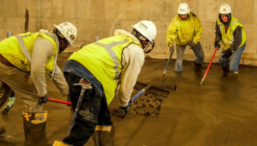 Workers flatten and level wet cement that will harden to be the buildings foundation.