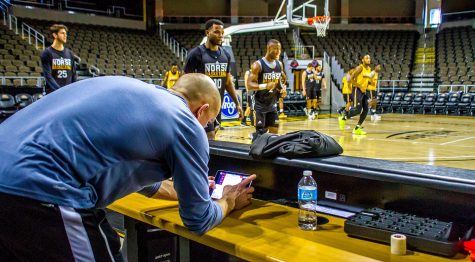 Brian Boos looks over the data from the Polar Pro on an iPad while the men's basketball team warm-ups for practice