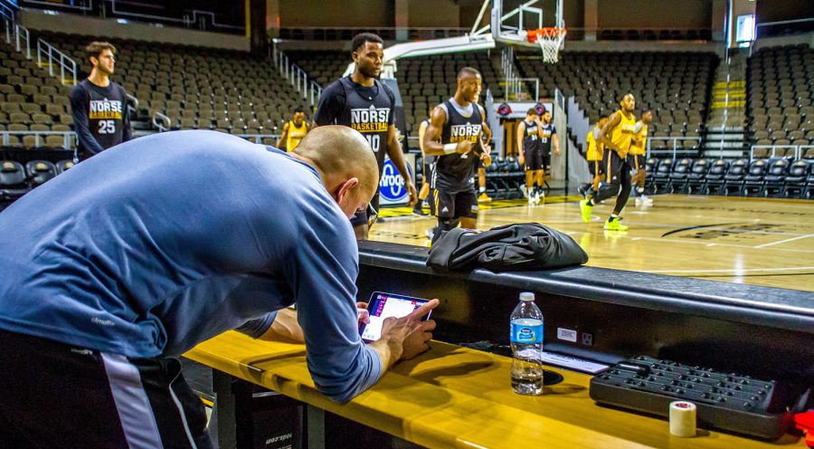 Brian Boos looks over the data from the Polar Pro on an iPad while the men's basketball team warm-ups for practice