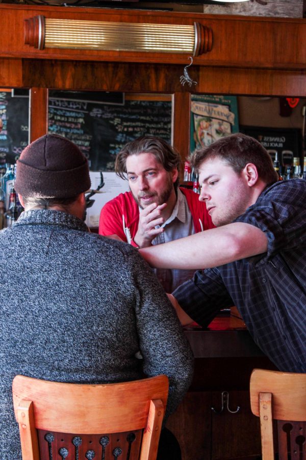 Weller gives directions to one of his actors while a crew member adjusts his microphone.