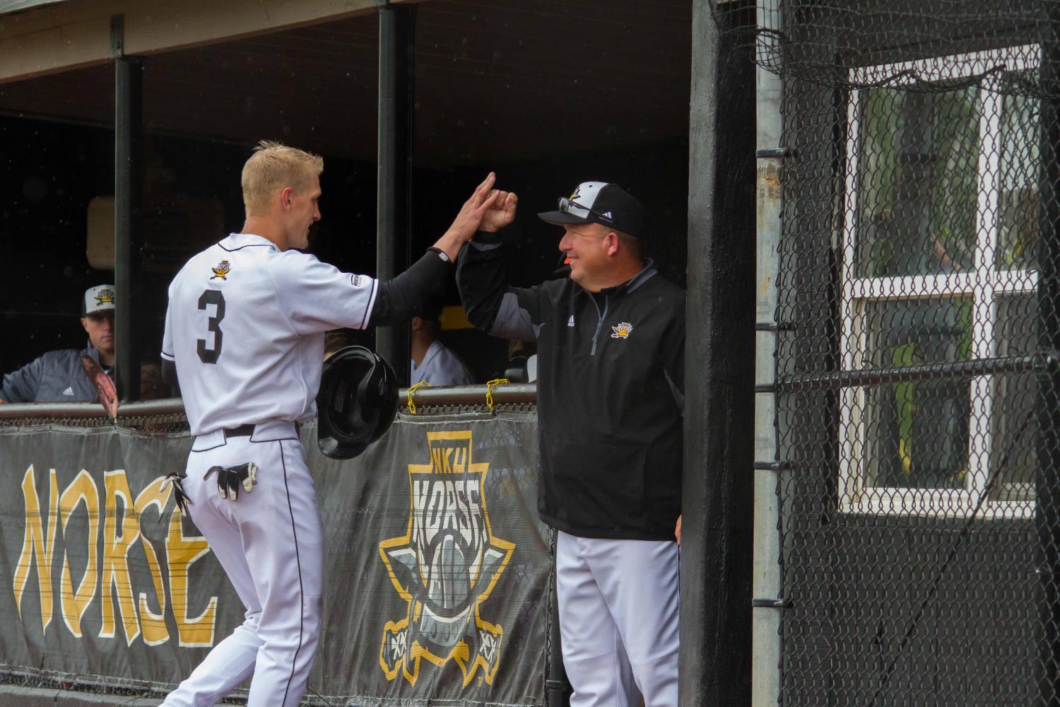 Coach Todd Asalon high fives Jake Richmond after Richmond scored a run against Oakland