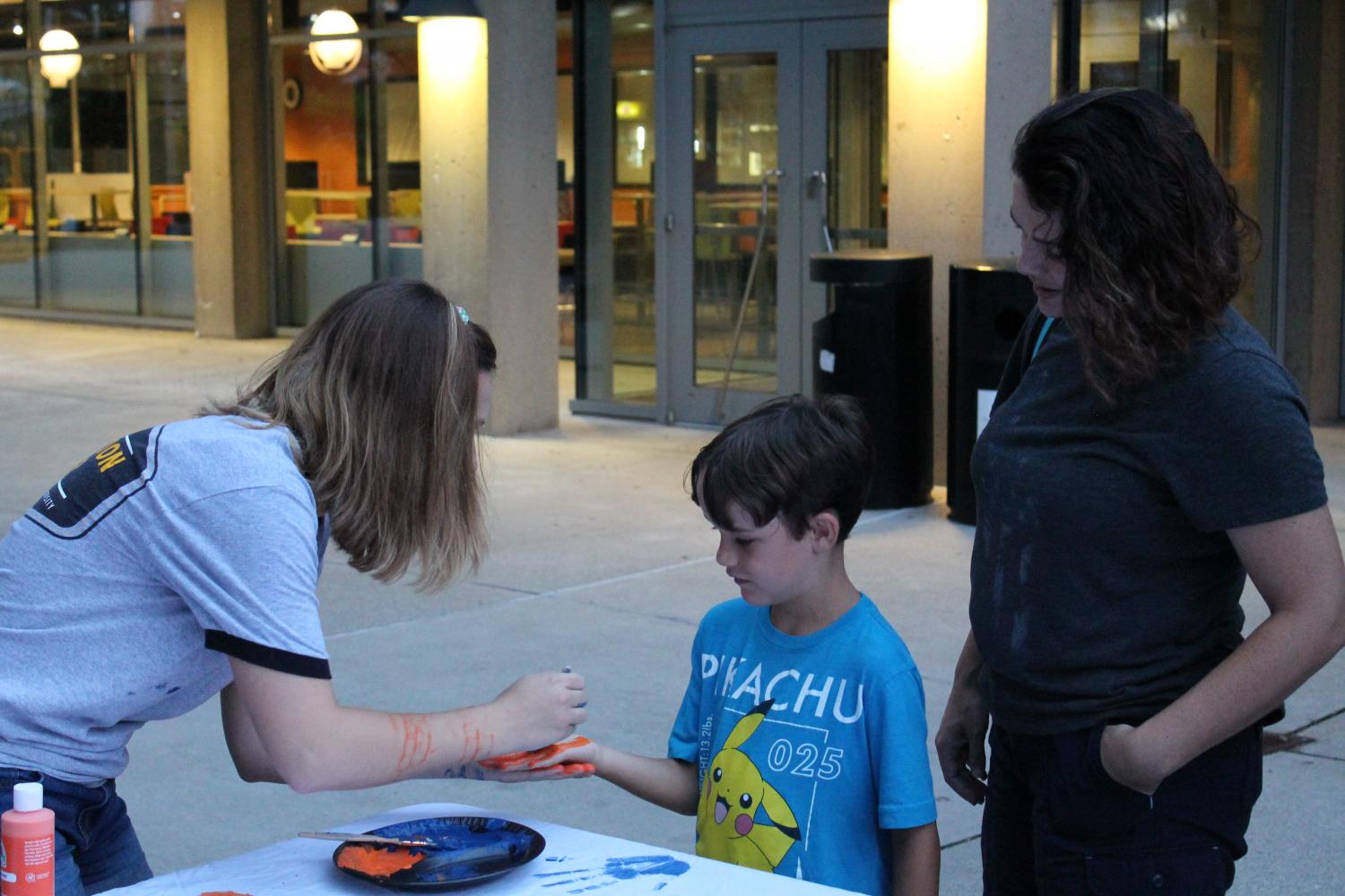 Community members, faculty, administration and  students turned out for the Vigil. Here, Edelen helps paint a childs hand. 