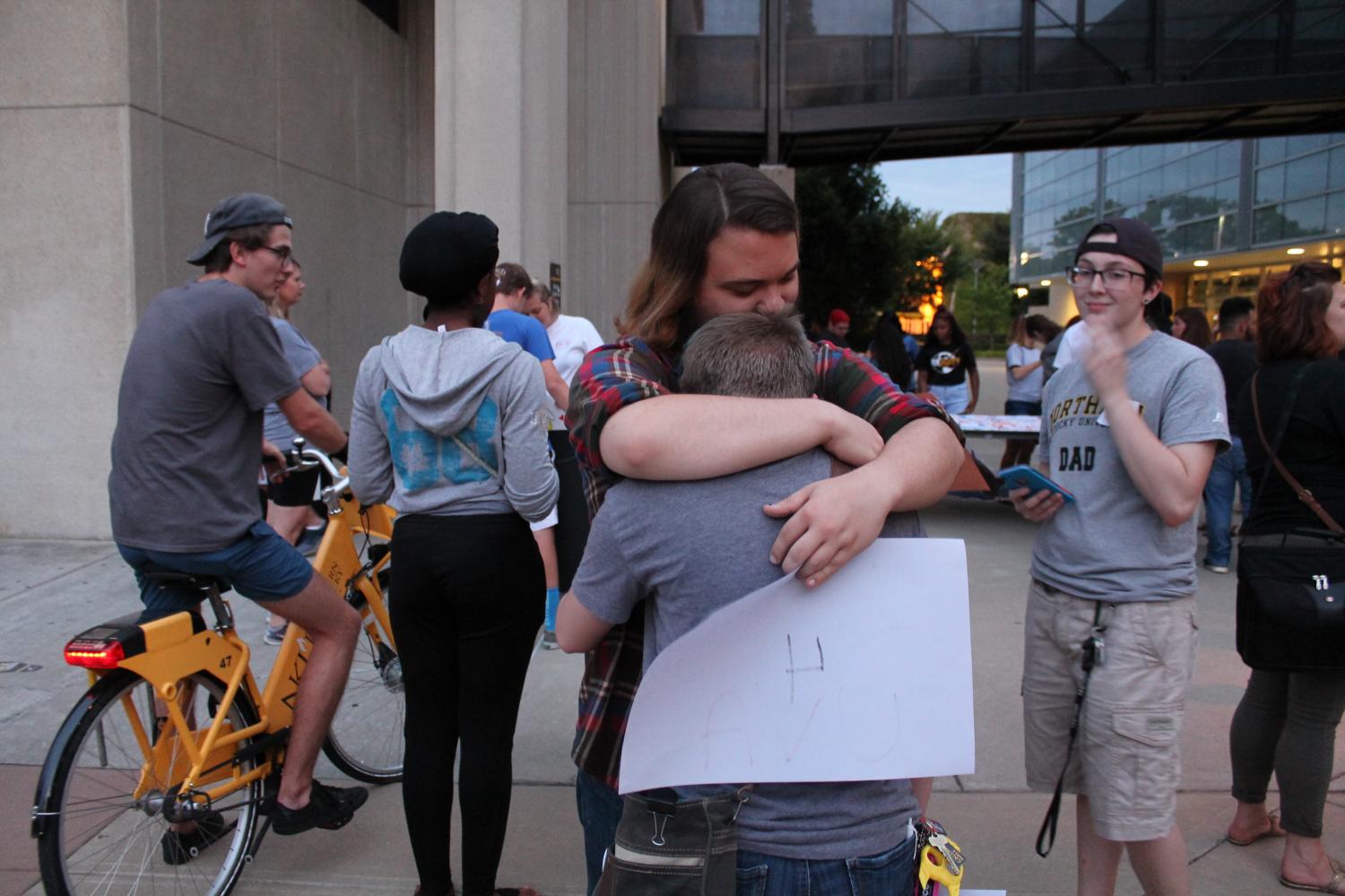 Many attendees hugged one another, speaking words of support. The sign that student Nova Grace holds reads #NKU4UVA. 