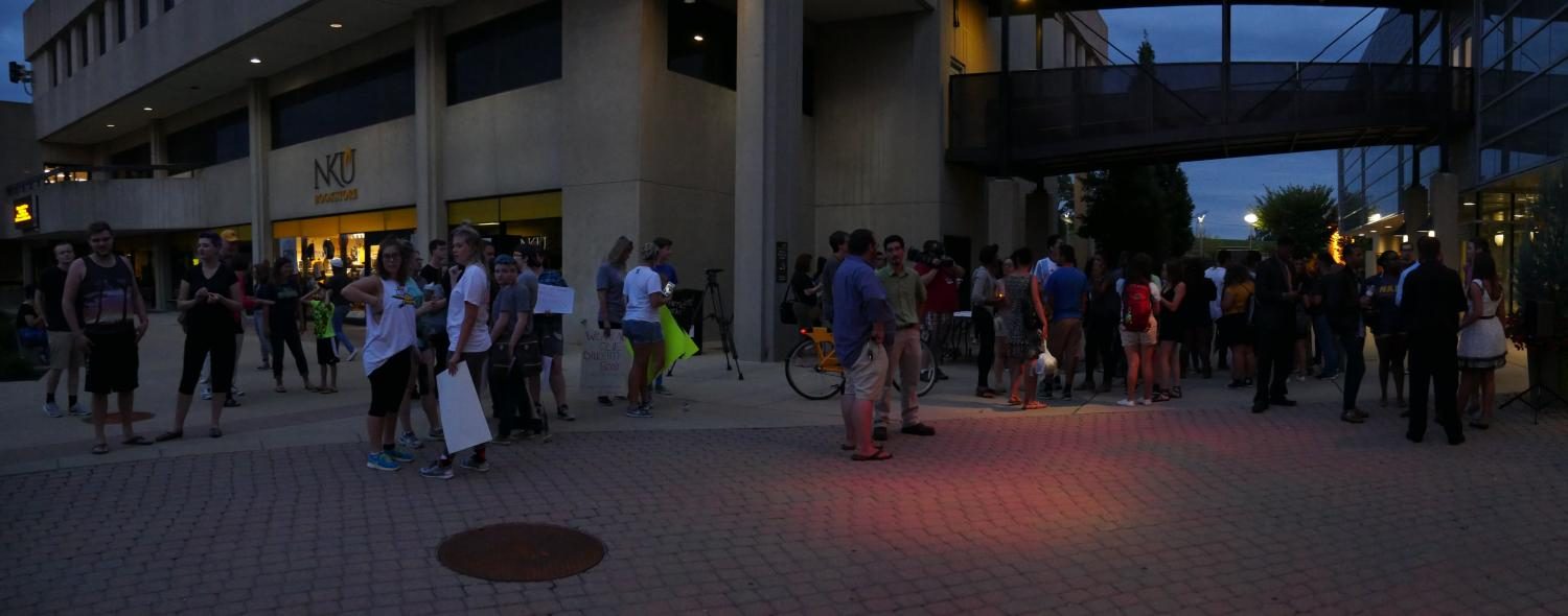 Attendees gathered along the SU plaza, later forming into a semi-circle shape. Some with posters, others with candles and painted hands. 