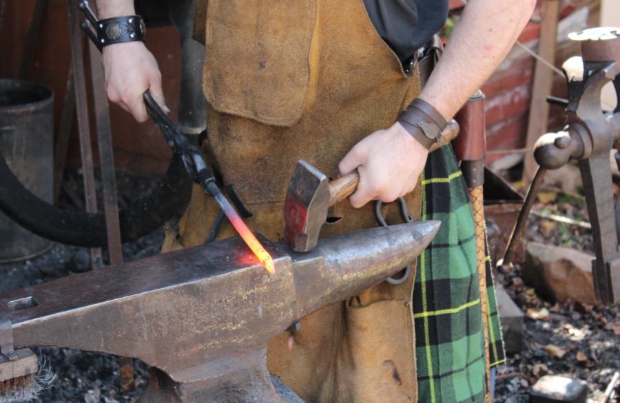 A blacksmith at the Dragon's Forge shapes red-hot metal with a hammer and anvil.
