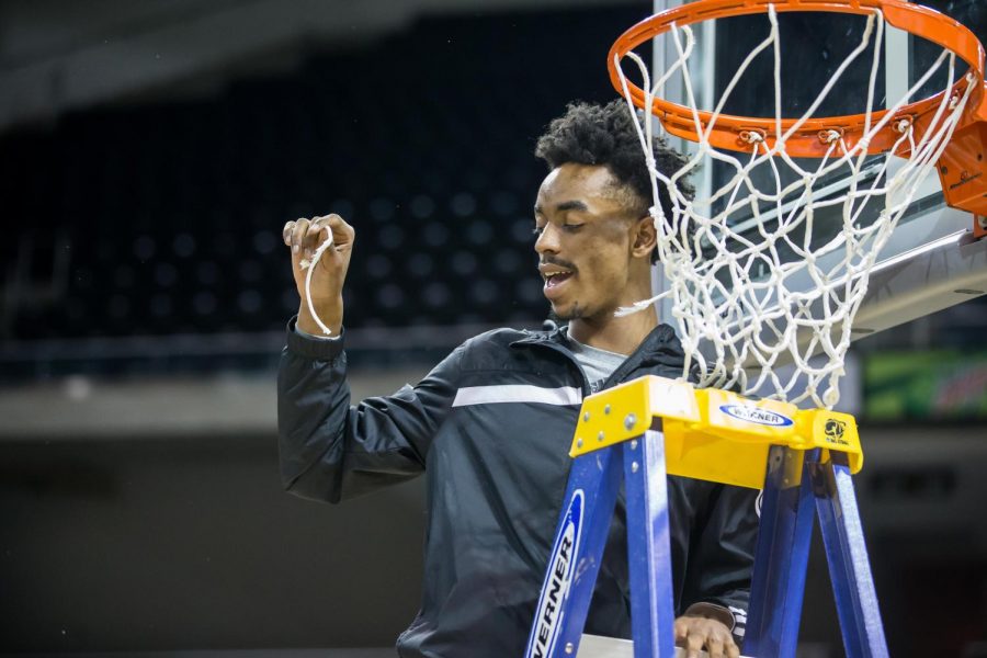 Jalen Tate (5) shows off his piece of the net after the men secured 1st place in the Horizon League.
