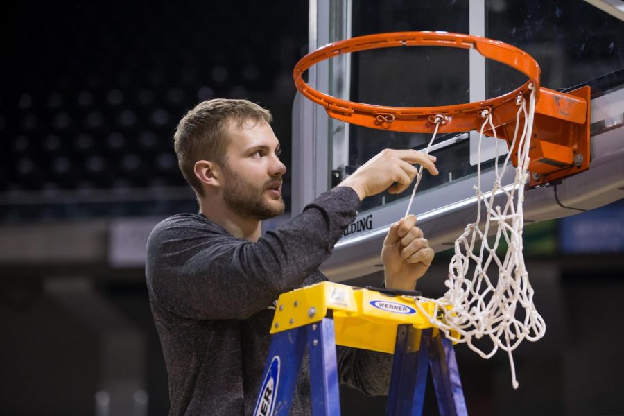 Carson Williams (23) cuts off his section of the net after securing 1st place in the Horizon League.