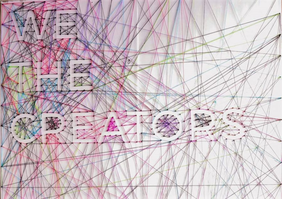 A web of colored yarn held together with thumbtacks forms the event's logo.