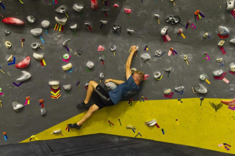 James Blazina attempts a challenging climbs route on the Campus Recreation Centers bouldering wall.