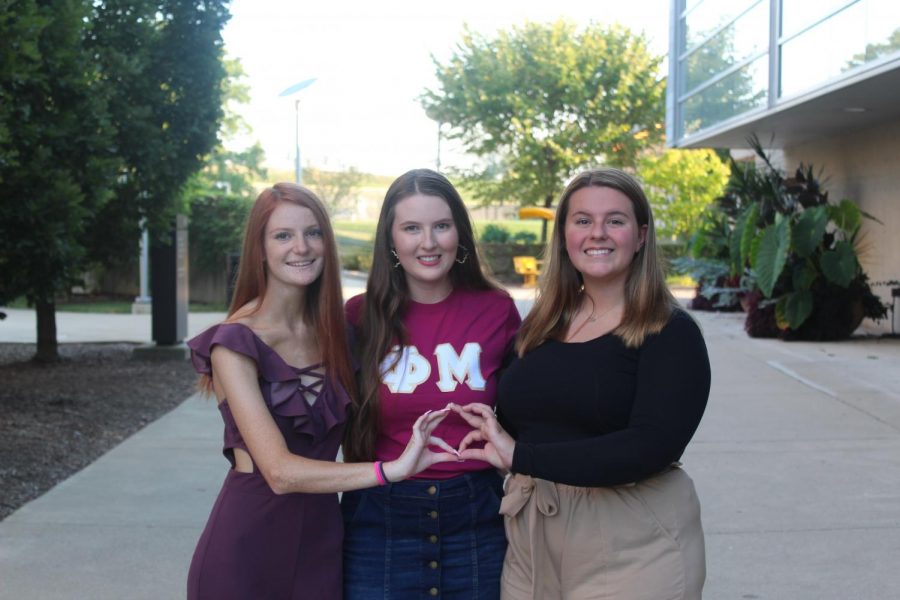 Brianna Collins, Rachel Henry, Gabby Manley pose with the Phi Mu hand sign. 