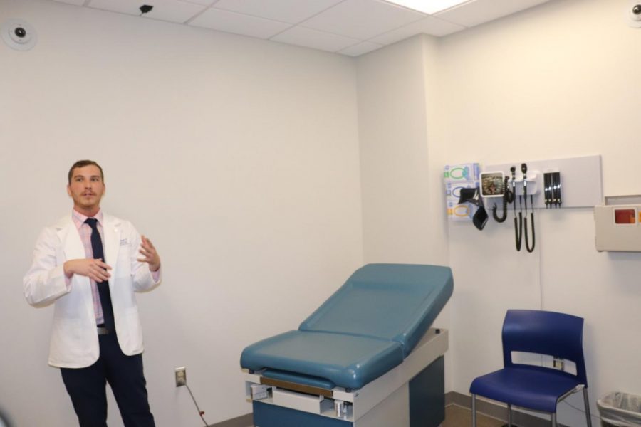 Aaron Adams, student of the College of Medicine, leading a tour of the facility, including this standardized patient room.