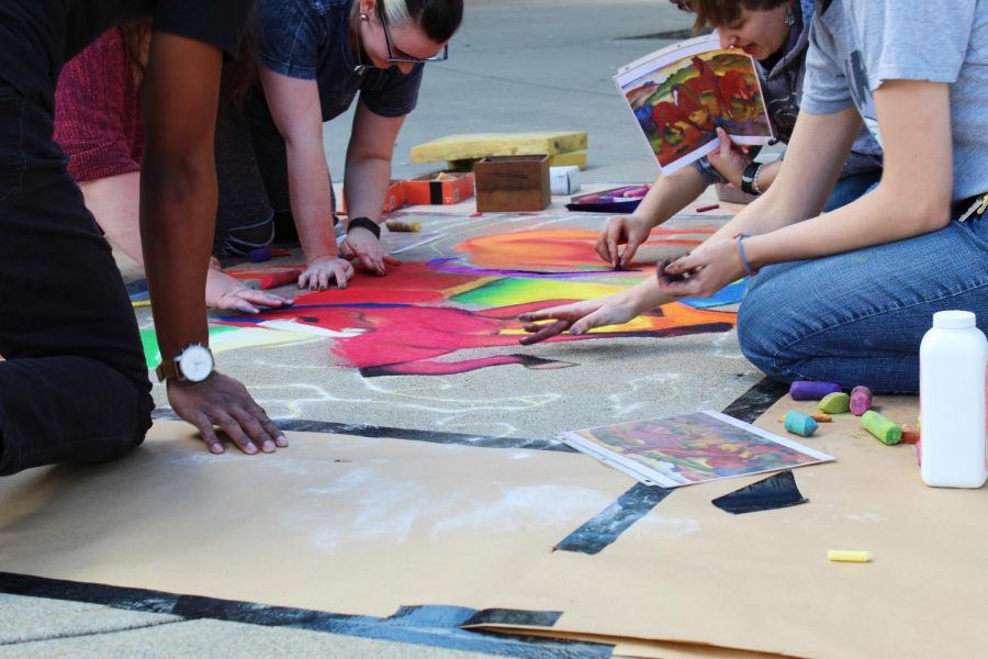 Students painting The Red Horses with chalk.