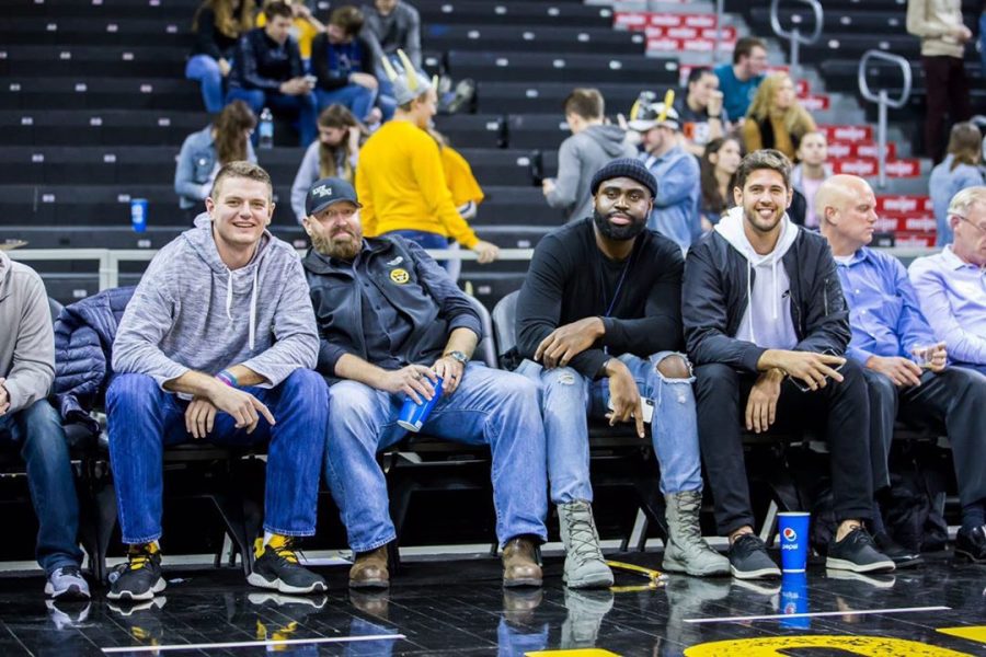 Men's Basketball Alum sit court-side at a basketball game.