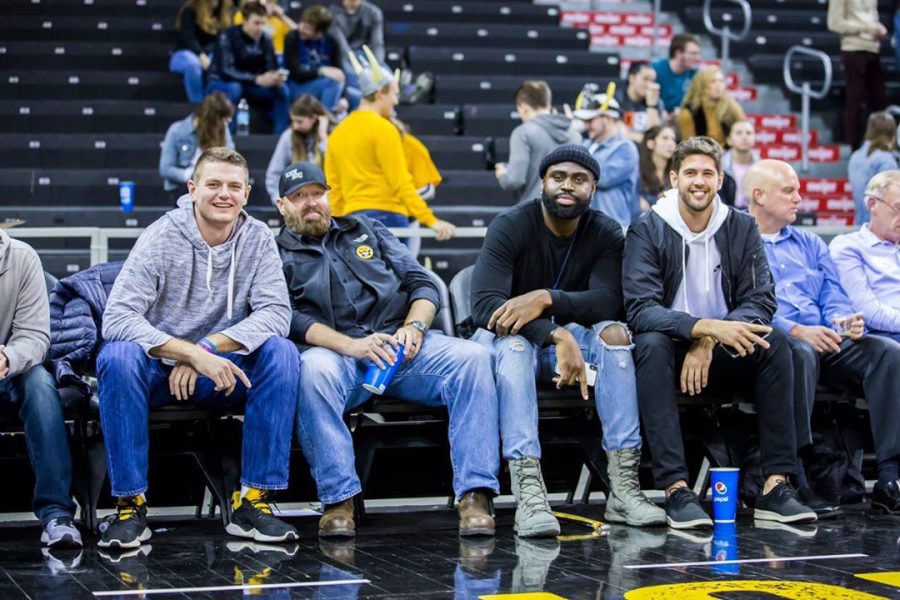 Mens Basketball Alum sit court-side at a basketball game.