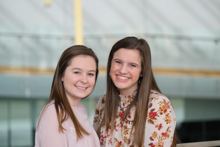 Lauren Goodwin, left, and Mia Derks, right, stand next to each other and smile. They are wearing light pink shirts.