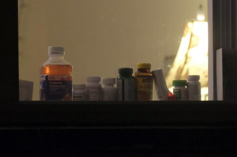 Various pill and vitamin bottles line a window. 