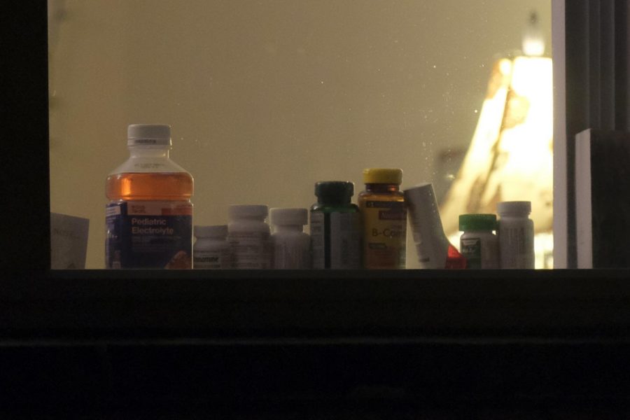Various pill and vitamin bottles line a window.