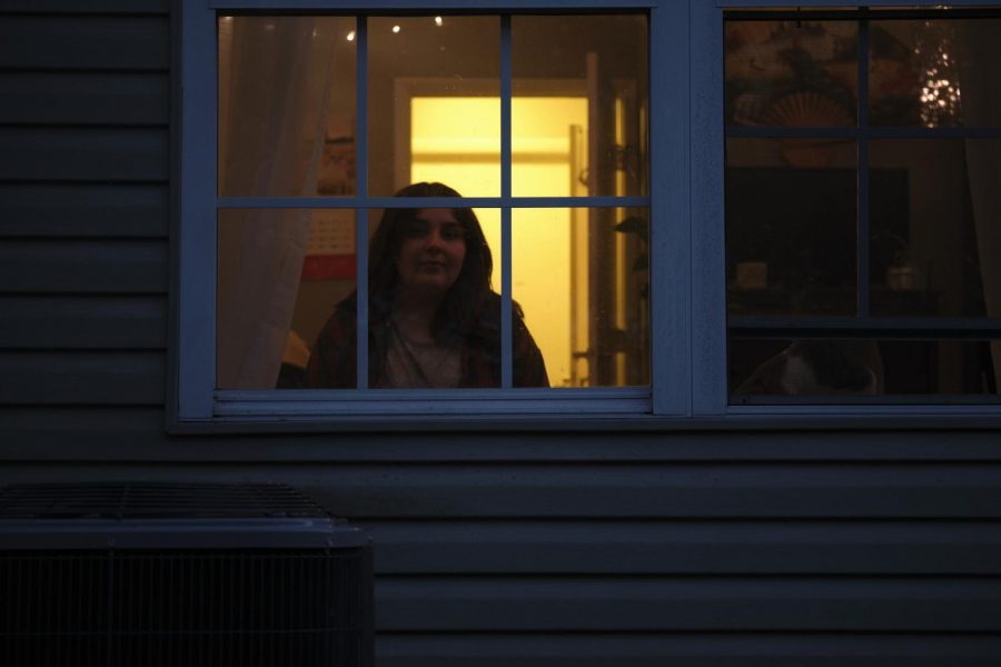 Bailey Fox sits inside her apartment through the bedroom window.