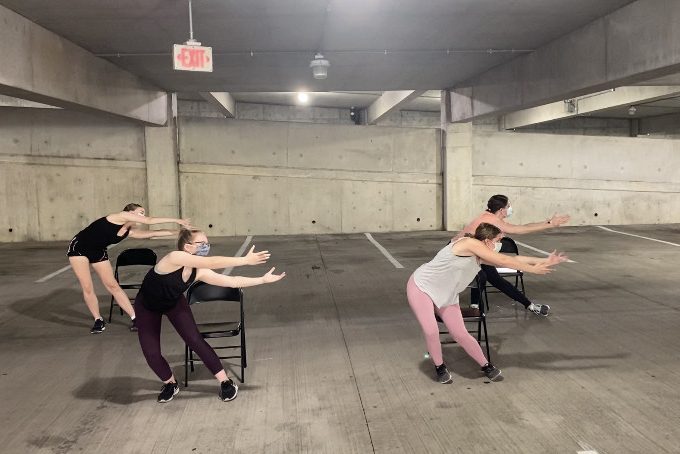 Four dancers rehearse in a parking garage.