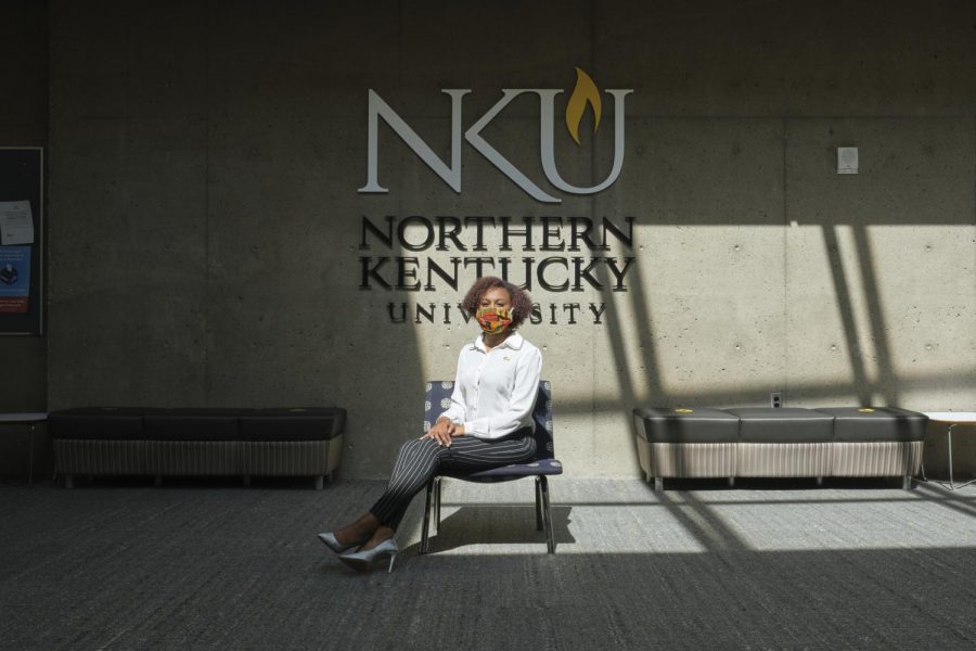 Kaitlin+Minniefield+sits+on+a+chair+in+front+of+an+NKU+logo.+Shes+wearing+a+white+shirt+and+black+pants.