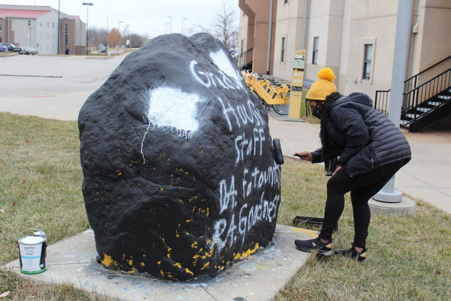 Hall Director Amira Bryant paints over the now covered logos.