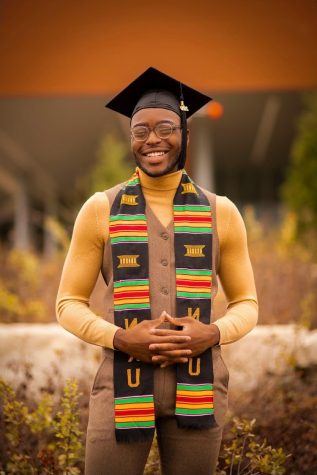 Jontay Brown is standing, smiling, wearing bright colors such as yellow, red and green on a graduation sash. He also is wearing a black graduation cap.