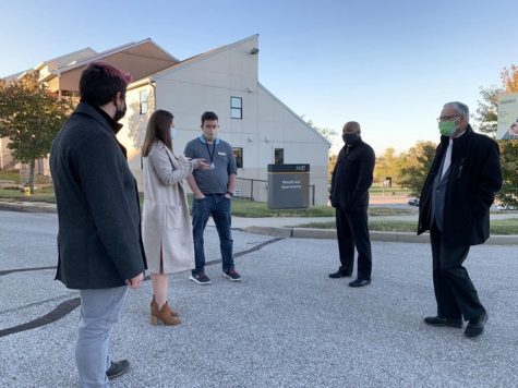 Goodwin outside wearing a coat and mask talking with others who are wearing masks.