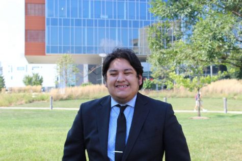 Ronald Delgado wearing a suit and smiling at the camera outside. 