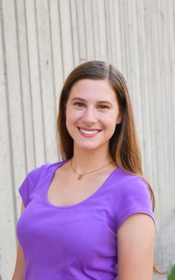 Alyssa Taylor standing wearing a purple shirt smiling at the camera.