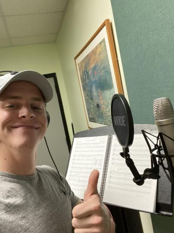 Jackson holding a thumbs up and smiling in front of a recording microphone. 